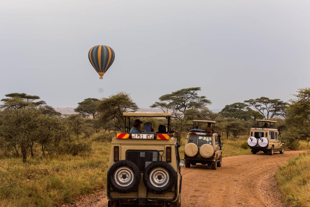 Flying Hot Air Balloon and Off-road Vehicles with Tourists on Safari in Tanzania